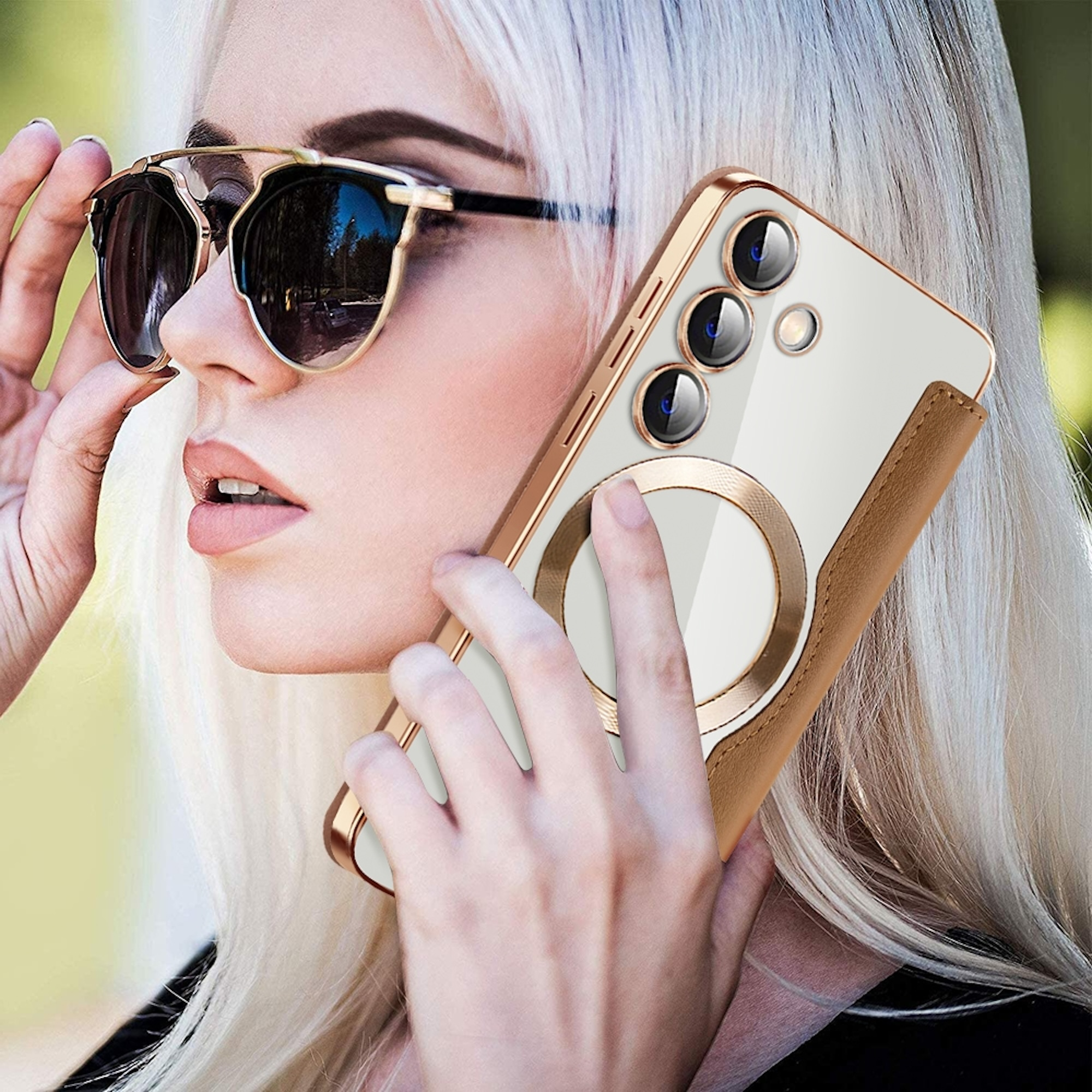 Blonde Frau mit Sonnenbrille telefoniert mit einem hellen Smartphone mit goldenem Etui.