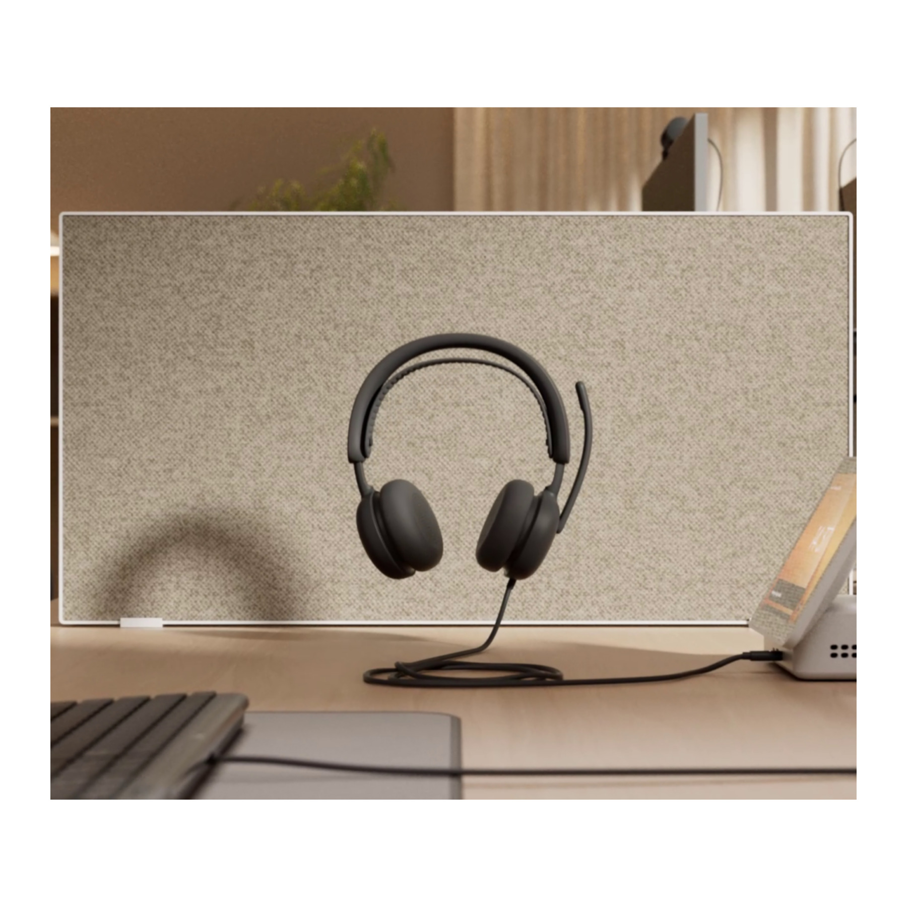 Auriculares negros con micrófono en un escritorio frente a un separador.