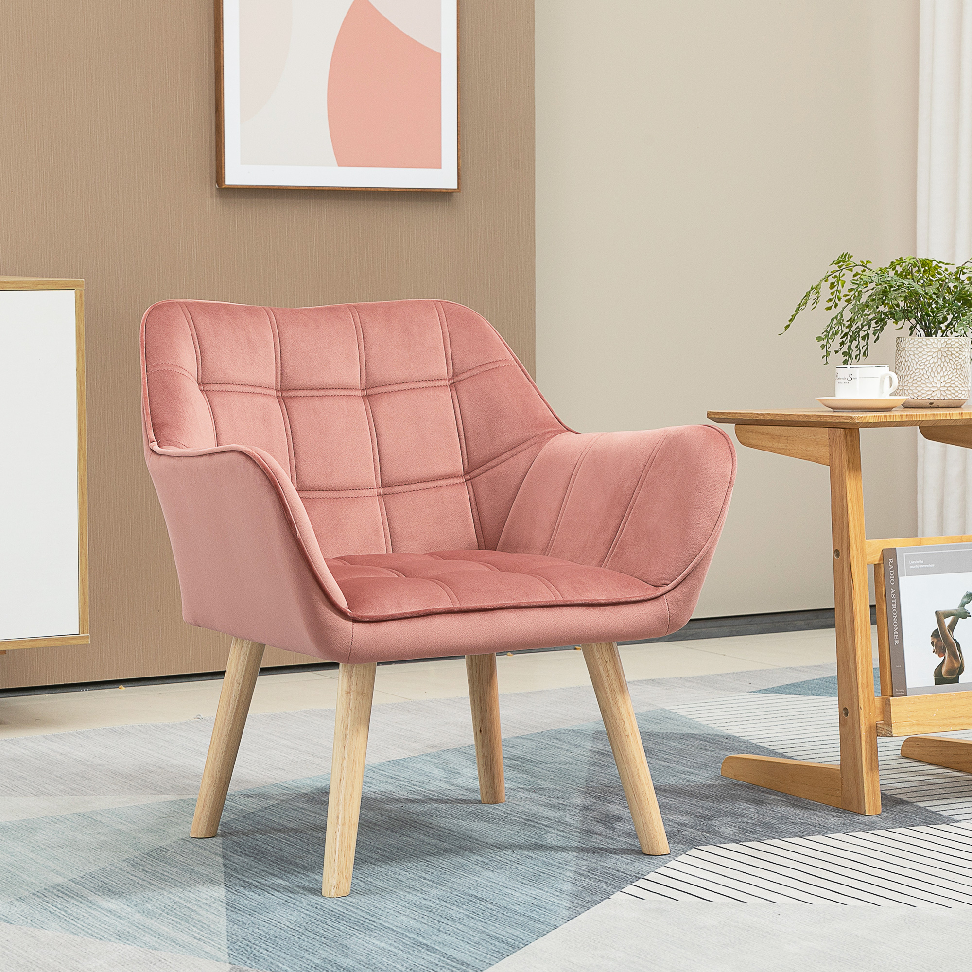 Una poltrona in velluto rosa con gambe in legno si trova su un tappeto fantasia in una stanza arredata modernamente.