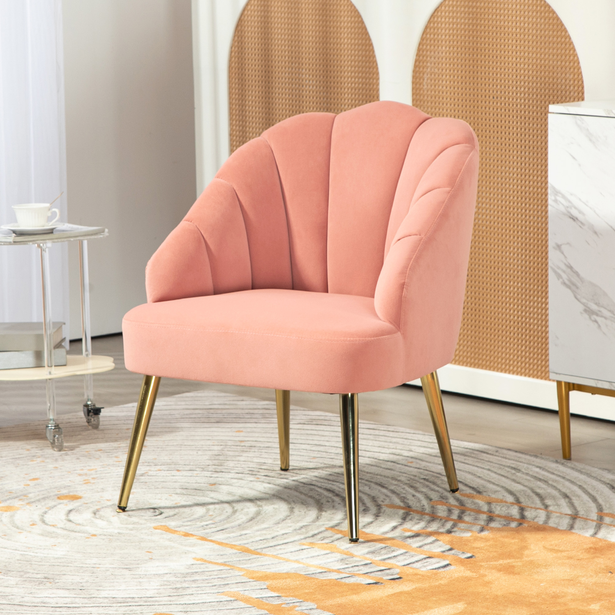 Una poltrona rosa a forma di conchiglia con gambe dorate su un tappeto grigio e oro.