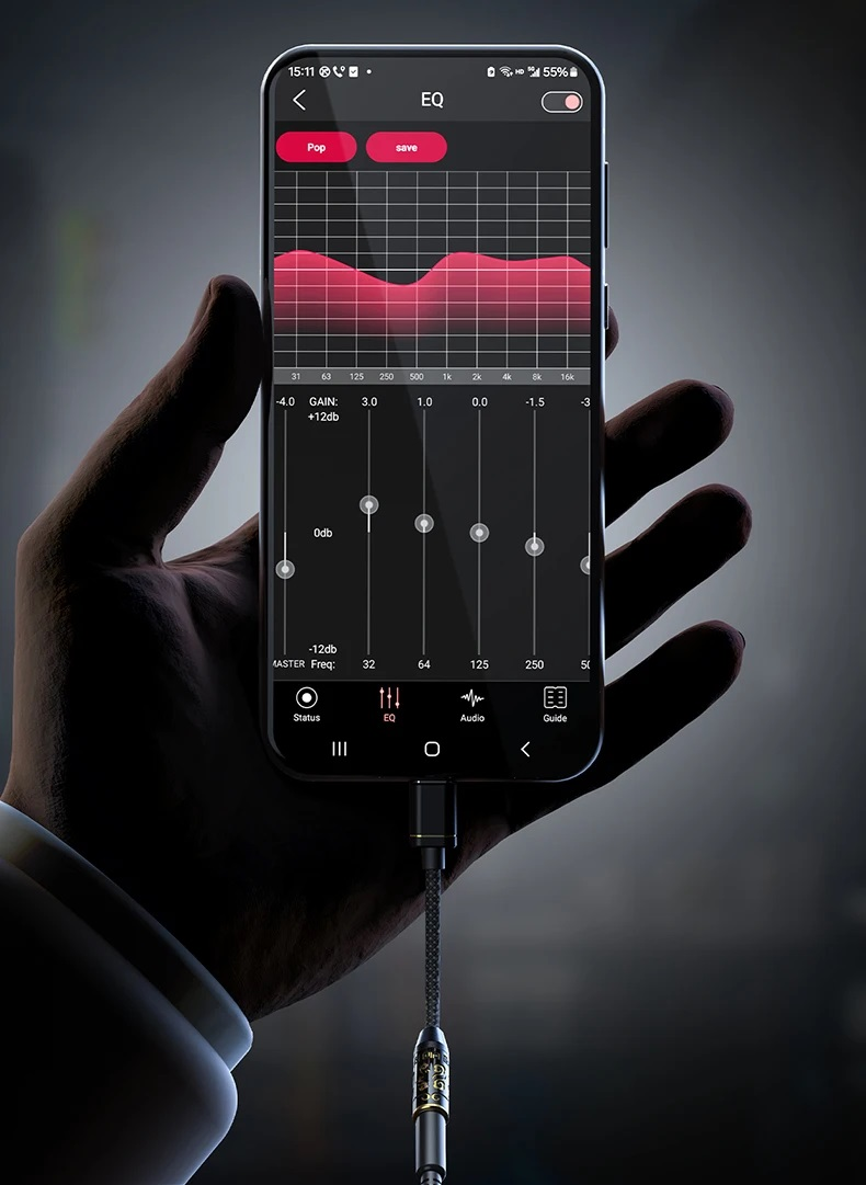 Una mano tiene uno smartphone che mostra una schermata di equalizzatore con un cavo audio collegato.