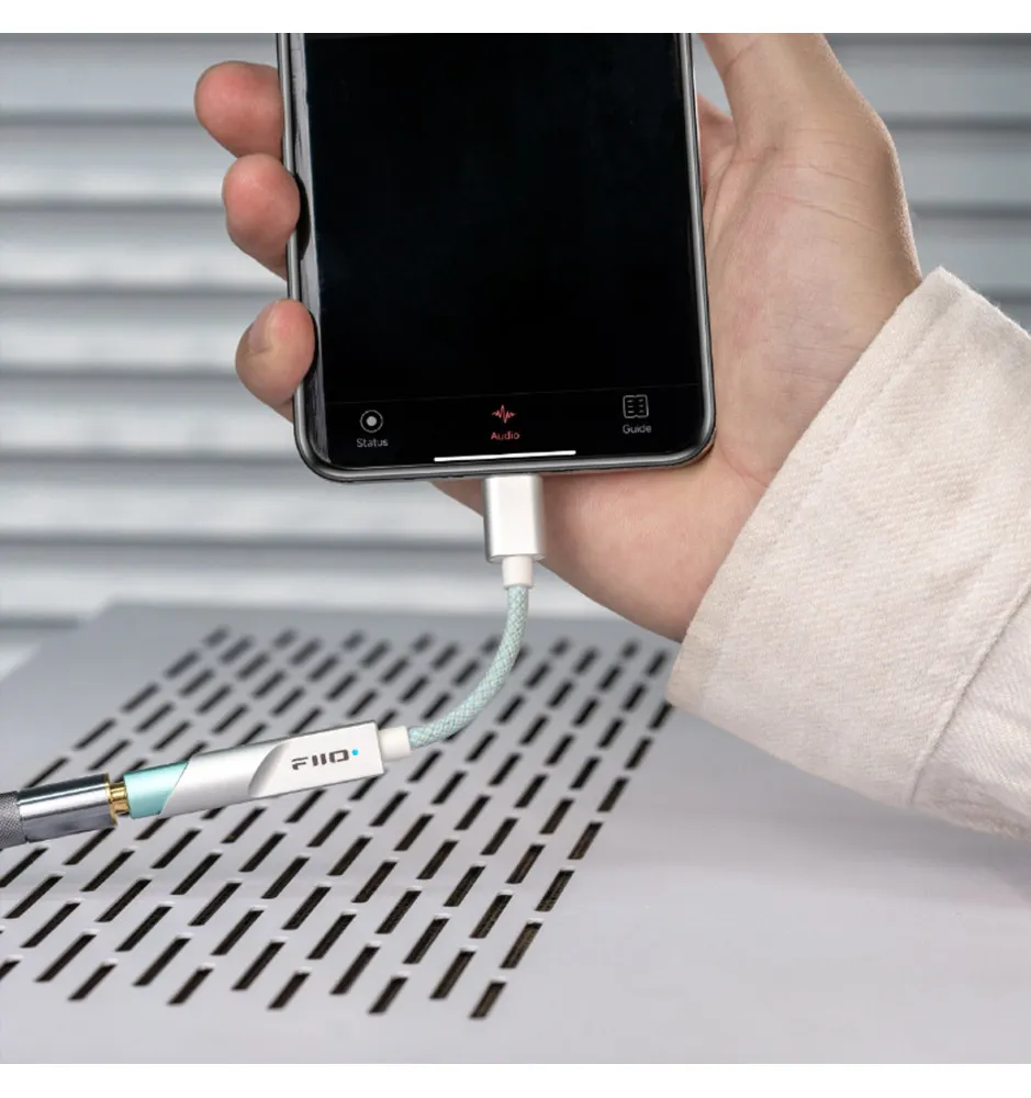 Teléfono con cable conectado a un dispositivo de audio plateado sobre un chasis ventilado.