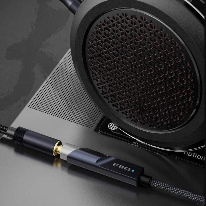 Primer plano de los auriculares FiiO con una almohadilla texturizada y un cable de audio conectado.