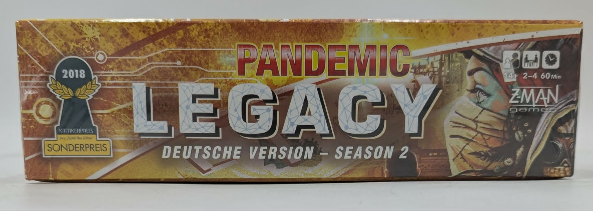 Verpackung der deutschen Version von Pandemic Legacy Season 2 mit gelbem Hintergrund und technischem Muster.