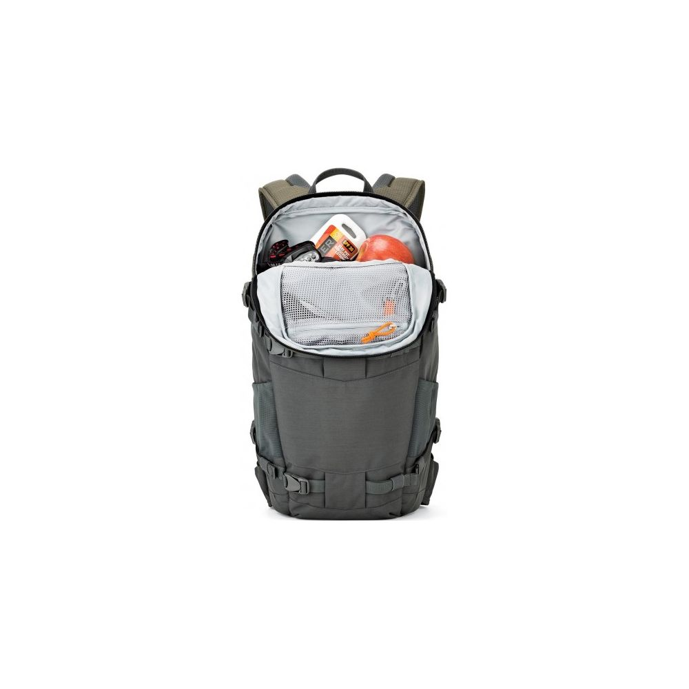 Ein offener, dunkelgrauer Rucksack auf weißem Hintergrund mit einem Apfel, Sonnencreme und Netztaschen im Inneren.