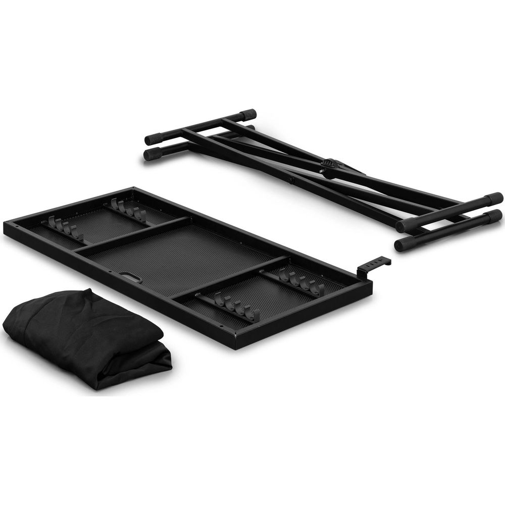 Una mesa de DJ negra desmontada con marco, tablero de malla y funda de tela sobre fondo blanco.