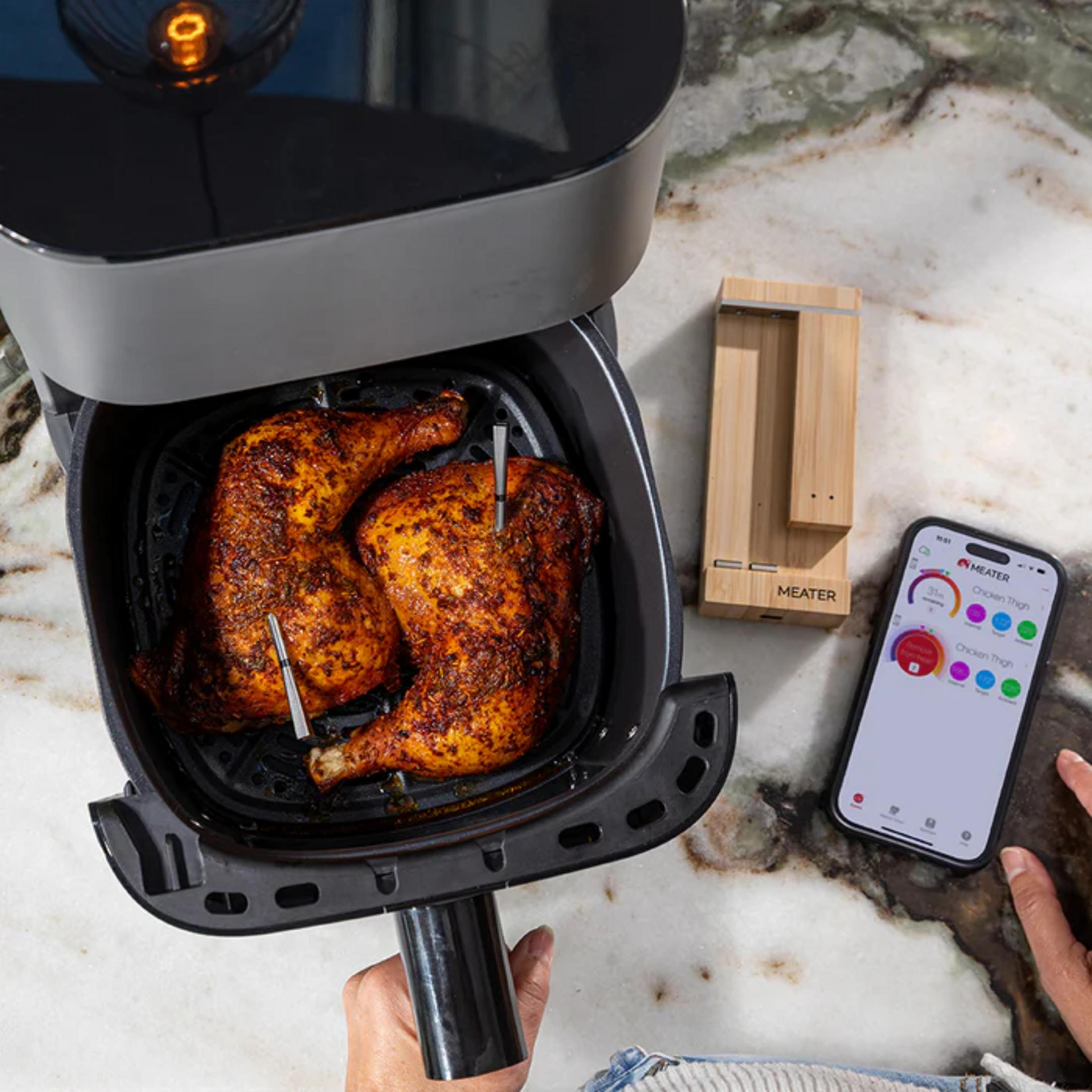 Cuisses de poulet croustillantes dans une friteuse, avec un thermomètre et un smartphone.