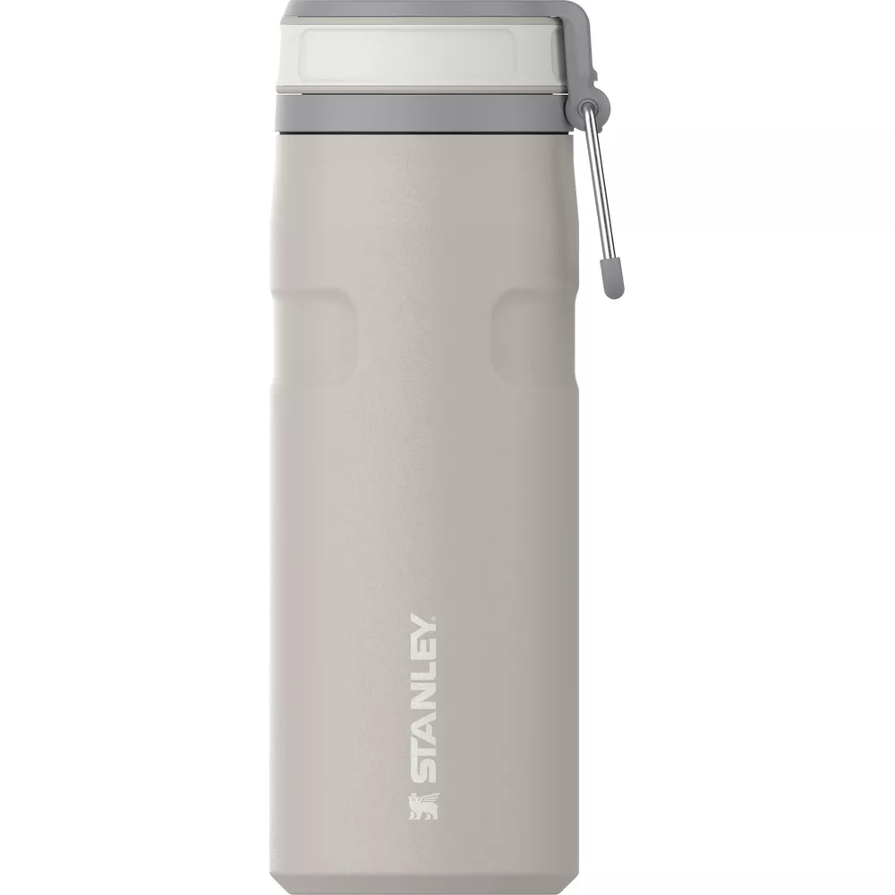Eine beigefarbene Stanley Thermosflasche mit graiem Deckel und Trageschlaufe vor weißem Hintergrund.