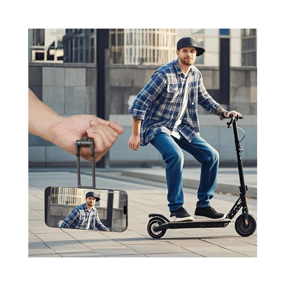 Una mano tiene uno smartphone con supporto, riprendendo un uomo su un monopattino elettrico.