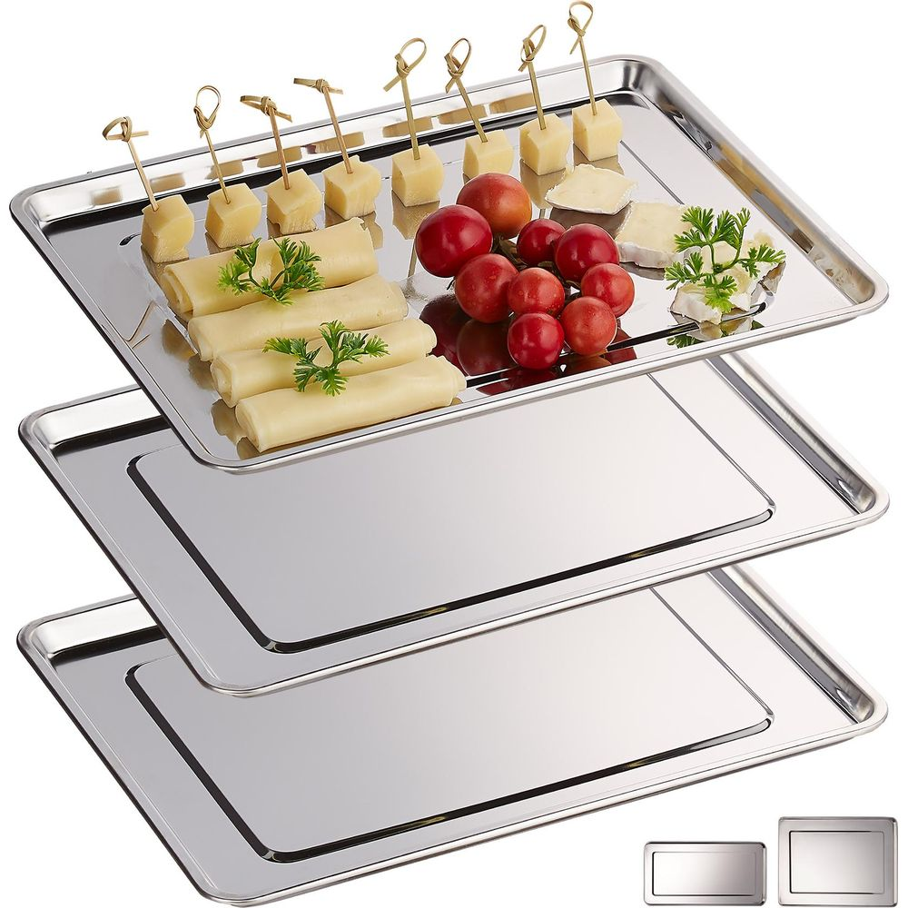 Drei Edelstahlbleche, das oberste mit Käseröllchen, gewürfeltem Käse auf Zahnstochern und kleinen roten Tomaten.