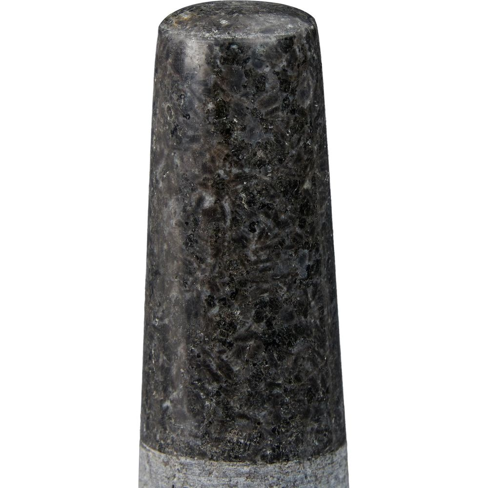 Ein zylindrischer Gegenstand aus dunklem, gemustertem Granit mit abgerundeter Spitze vor weißem Hintergrund.