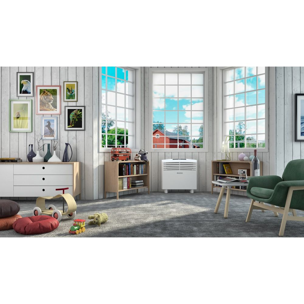 Stanza luminosa con pareti in legno bianco, ampie finestre, condizionatore bianco e poltrona verde.