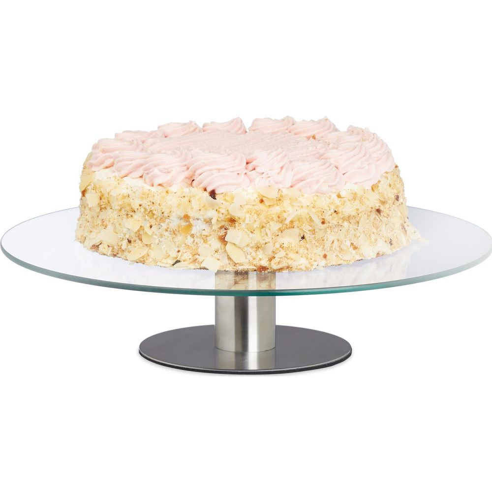 Eine runde Torte mit rosa Creme und Nüssen auf einer Glas-Kuchentorte.