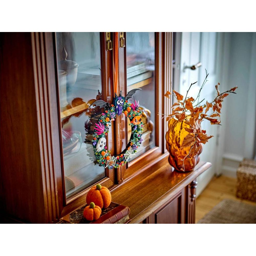 Un mobile in legno decorato con una colorata ghirlanda di Halloween, zucche e foglie autunnali.