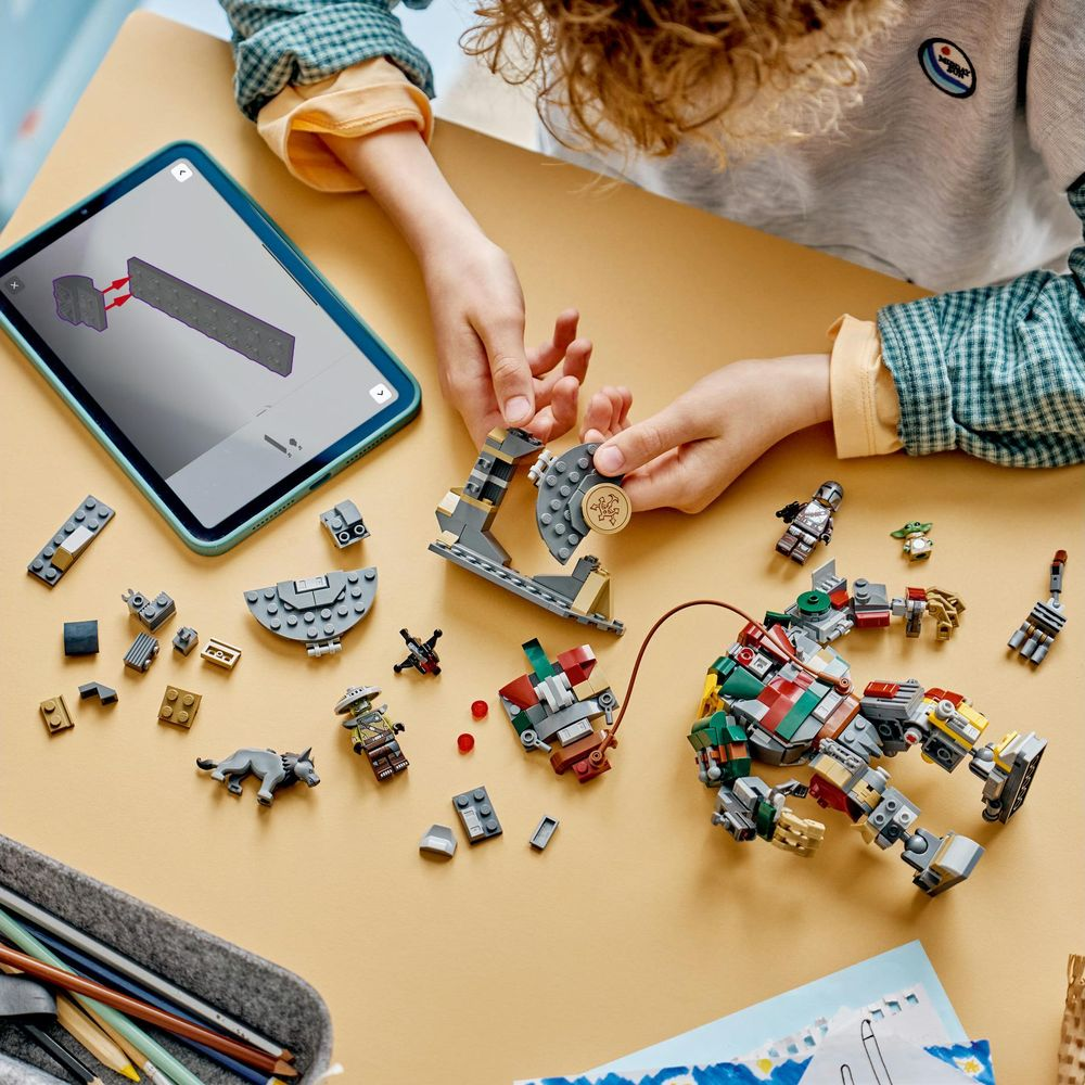 Un niño construye modelos de Lego en una mesa con instrucciones en una tableta.