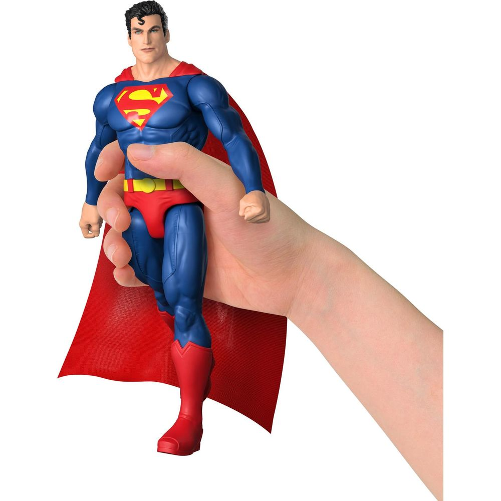 Una mano sostiene una figura de acción de Superman con capa roja sobre fondo blanco.