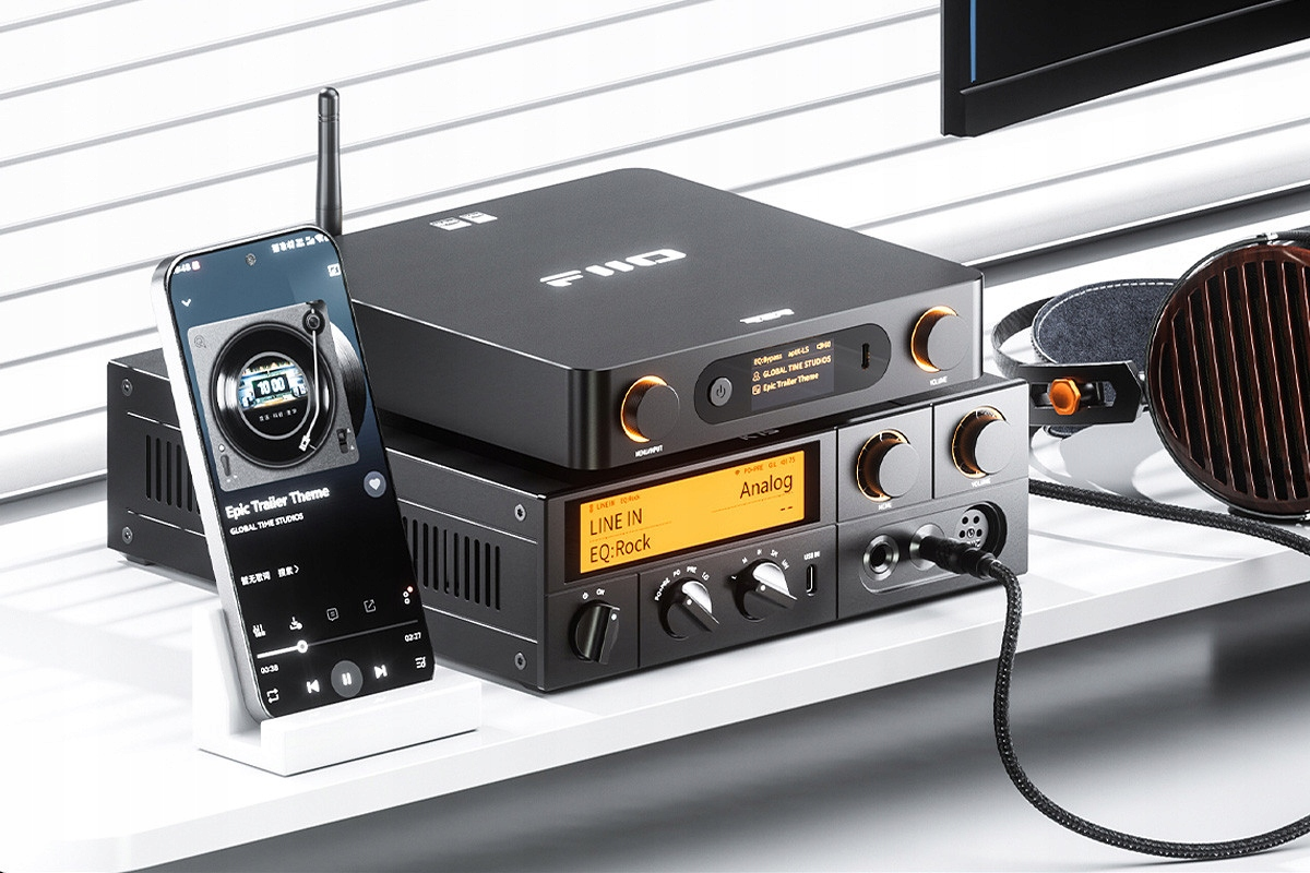 Czarne urządzenia audio FiiO, smartfon na stojaku i słuchawki na półce.