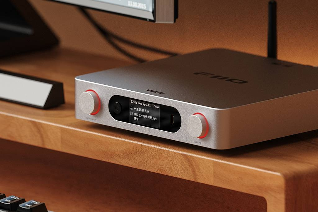 Un reproductor de audio plateado con una perilla roja descansa en un escritorio de madera.
