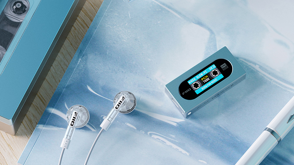 Un reproductor MP3 azul con pantalla, auriculares blancos y un cassette sobre una superficie clara.