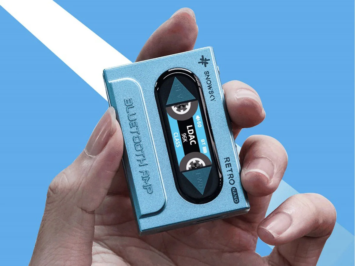 Una mano sostiene un amplificador Bluetooth Retro Nano azul que parece una cinta de cassette.
