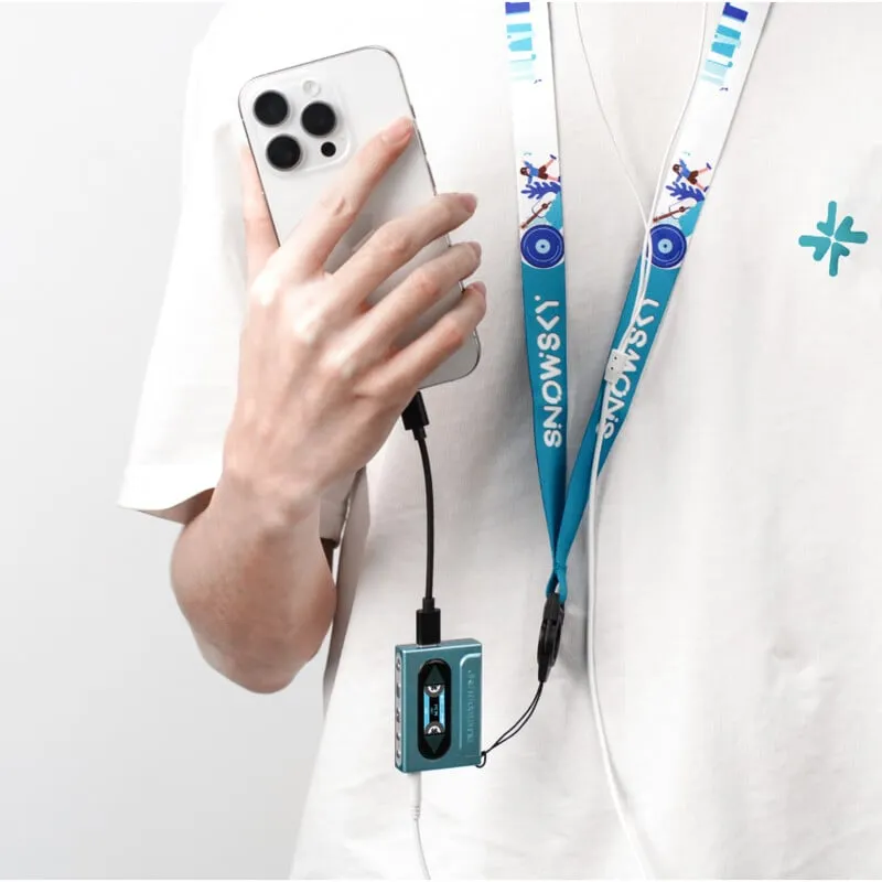 Una persona con camisa blanca sostiene un teléfono inteligente conectado a un pequeño reproductor de música azul y auriculares.
