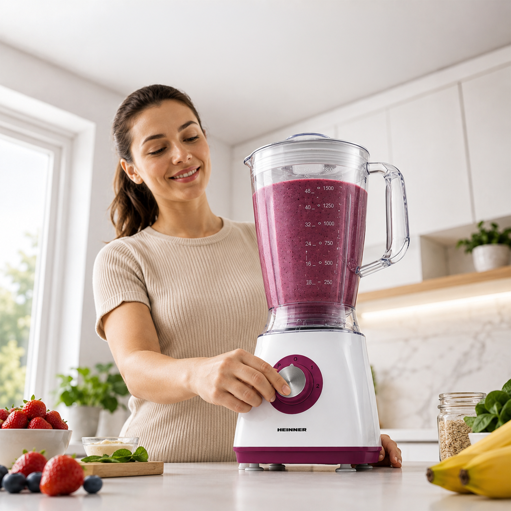 Eine lächelnde Frau bedient einen weißen Standmixer mit violettem Smoothie in einer modernen Küche.