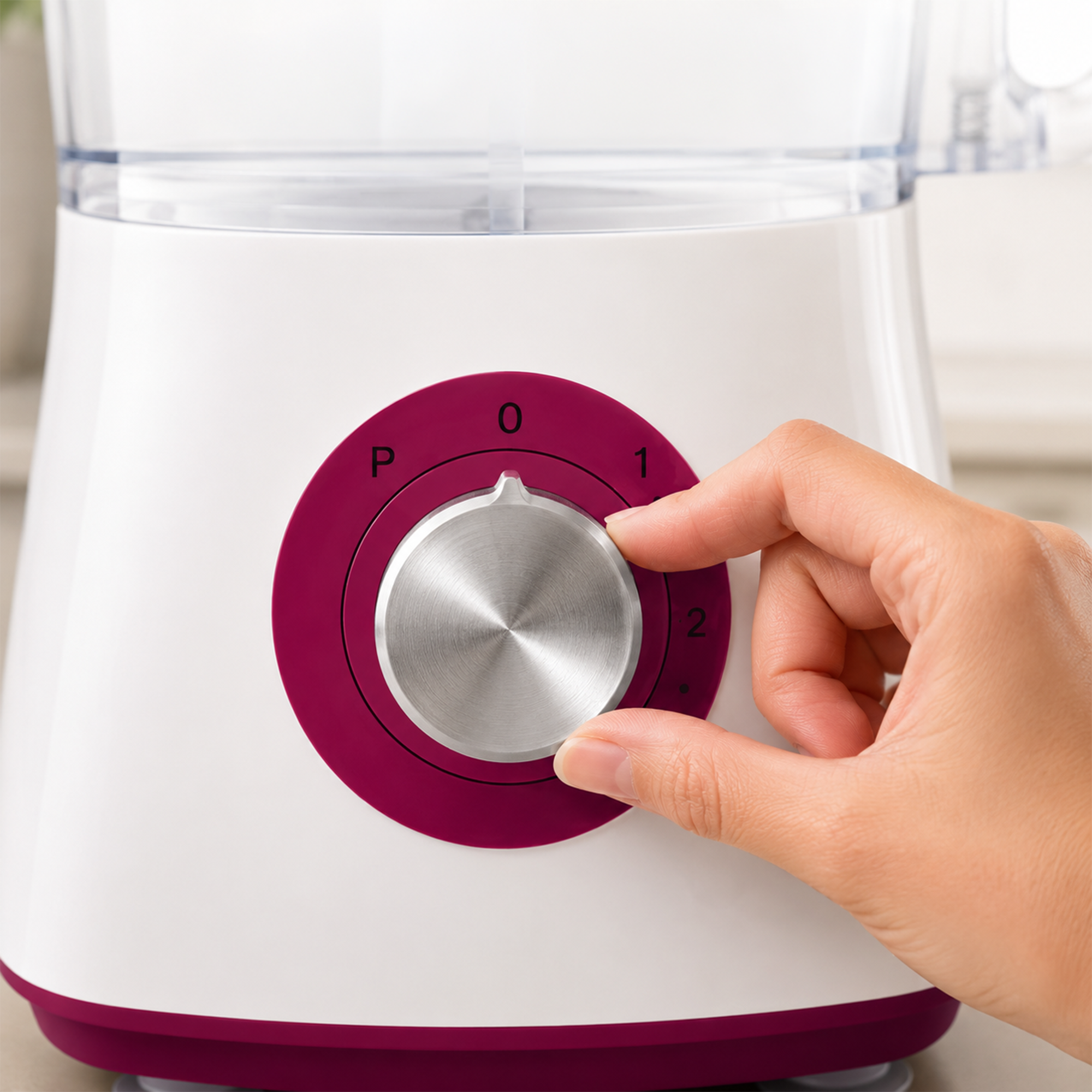 Eine Hand dreht den silbernen Drehknopf eines weißen Mixers mit rotem Ring auf Stufe 1.