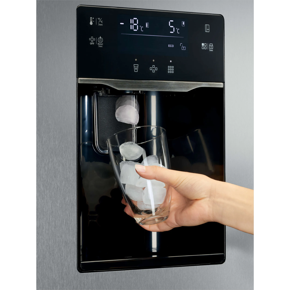 Una mano sostiene un vaso mientras caen cubitos de hielo de un dispensador.