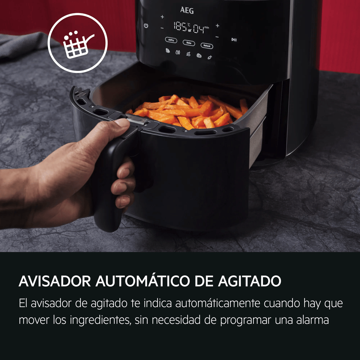Una mano saca la cesta de una freidora de aire negra llena de patatas fritas.