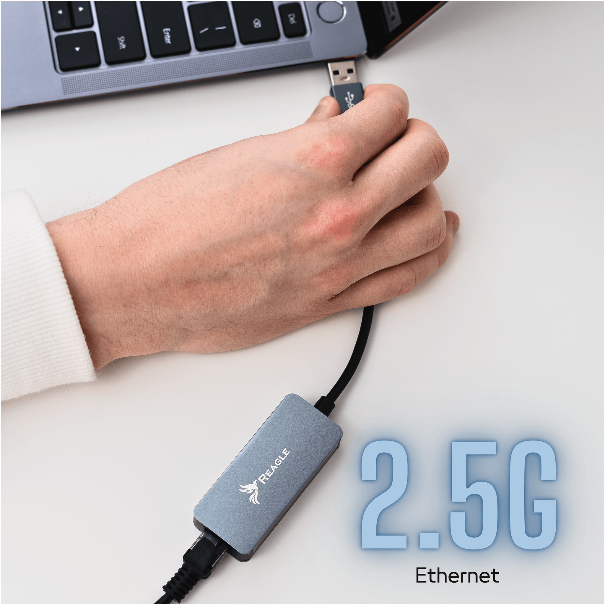 Ręka podłącza szary adapter Ethernet REAGLE do portu USB laptopa.