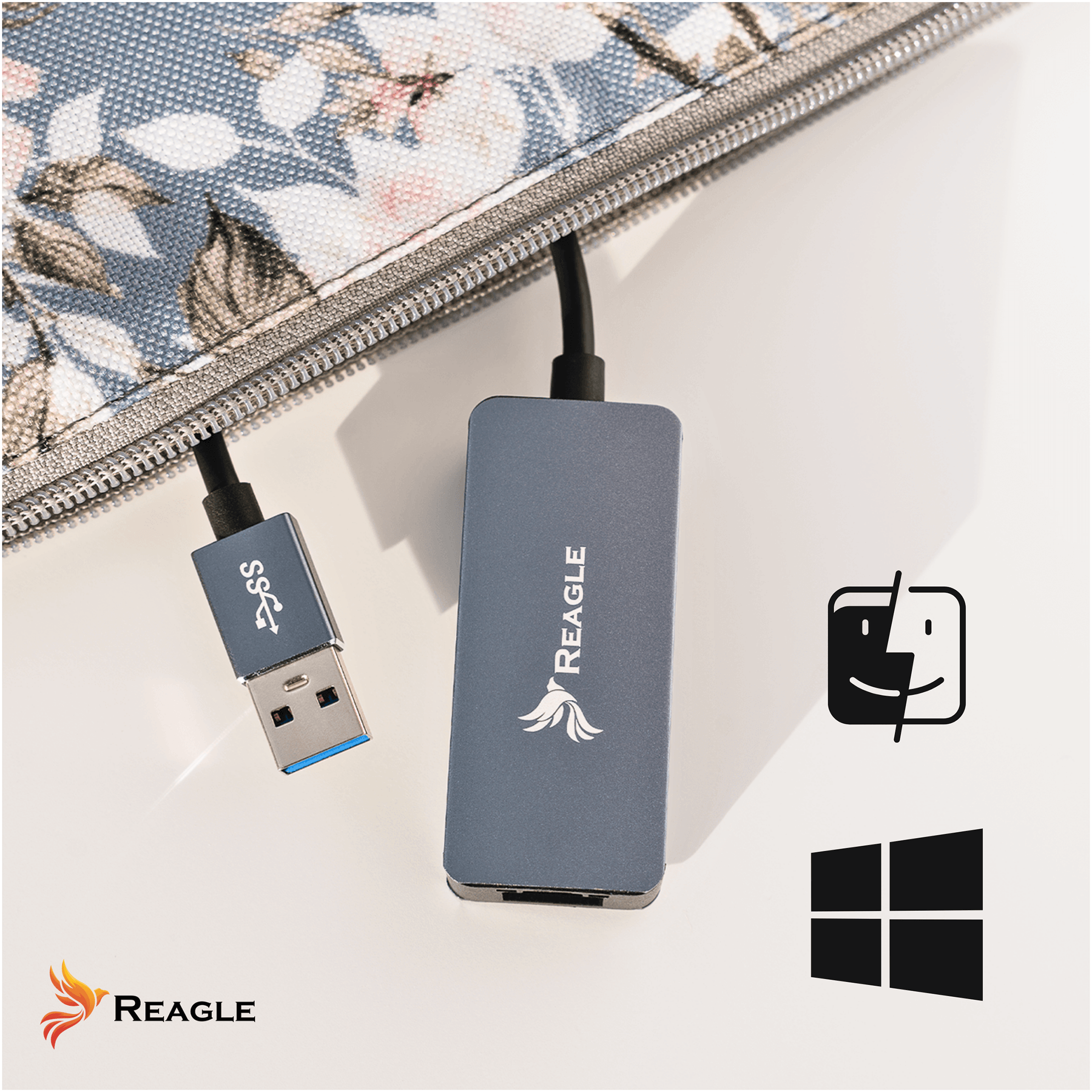 Szary hub USB Reagle i kabel podłączone do wzorzystego etui na białym stole.