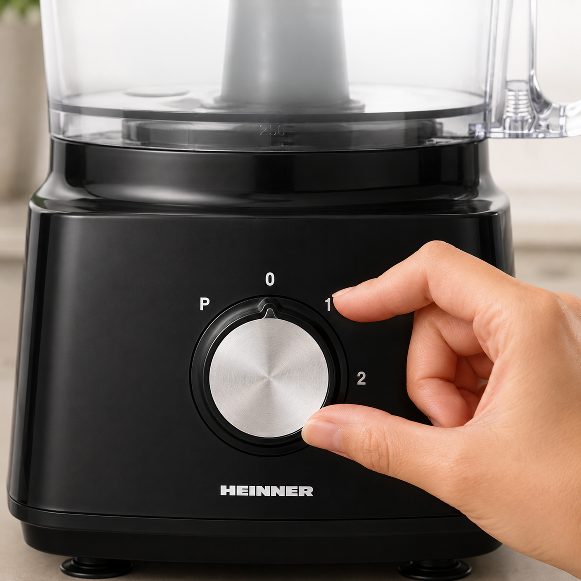 Eine Hand dreht den silbernen Drehregler einer schwarzen Heinner Küchenmaschine auf Stufe 1.