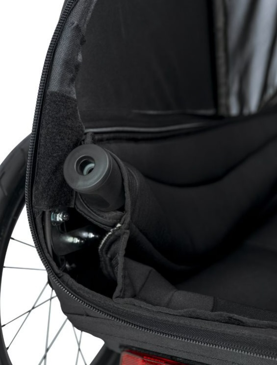 Primer plano del interior de un remolque de bicicleta para niños negro con asiento acolchado.