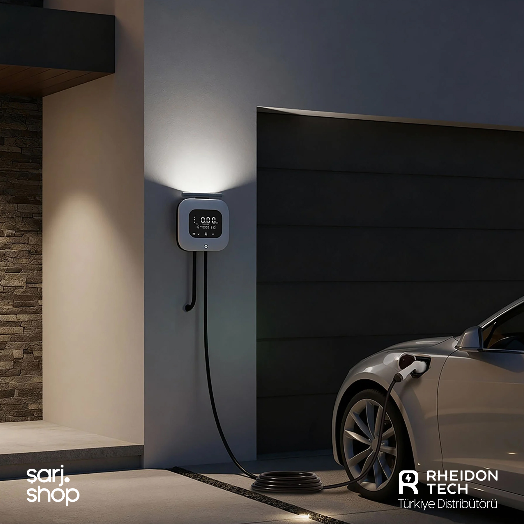 Gümüş renkli bir elektrikli araba garaj önünde park edilmiş ve duvara monte şarj cihazıyla şarj oluyor.
