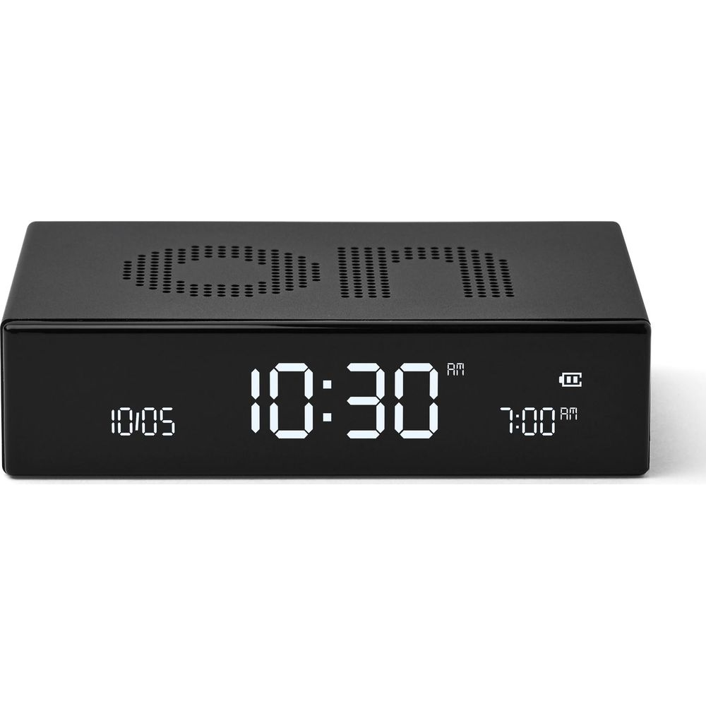 Ein schwarzer digitaler Wecker zeigt 10:30 Uhr an, mit weißem LED-Display und Datumsanzeige auf weißem Hintergrund.