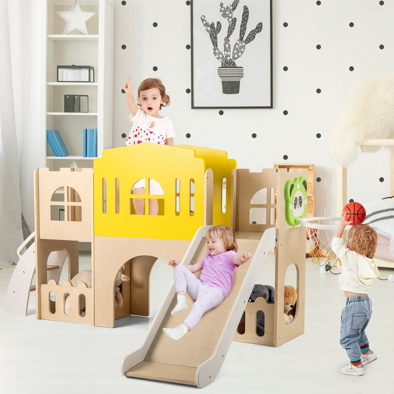 Des tout-petits jouent dans une salle de jeux moderne avec château d'escalade en bois et toboggan.