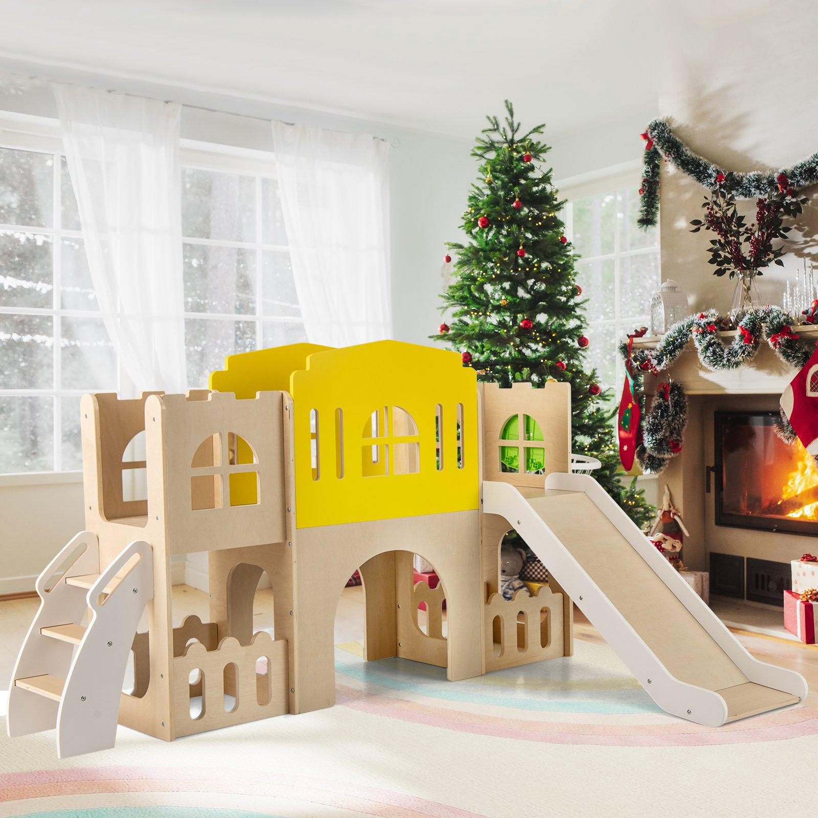 Un château d'escalade en bois avec un mur jaune, un toboggan et des escaliers dans une pièce festive avec un sapin.