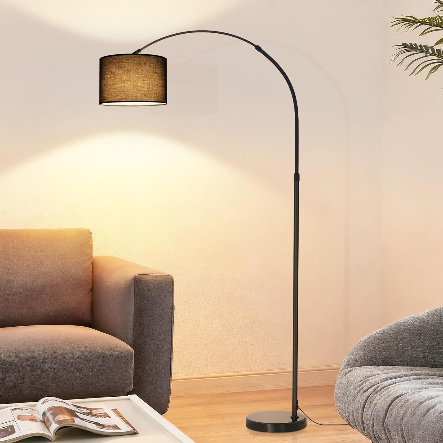 Eine schwarze Bogenstehlampe beleuchtet die Wand neben einem Sofa in einem hellen Wohnzimmer.