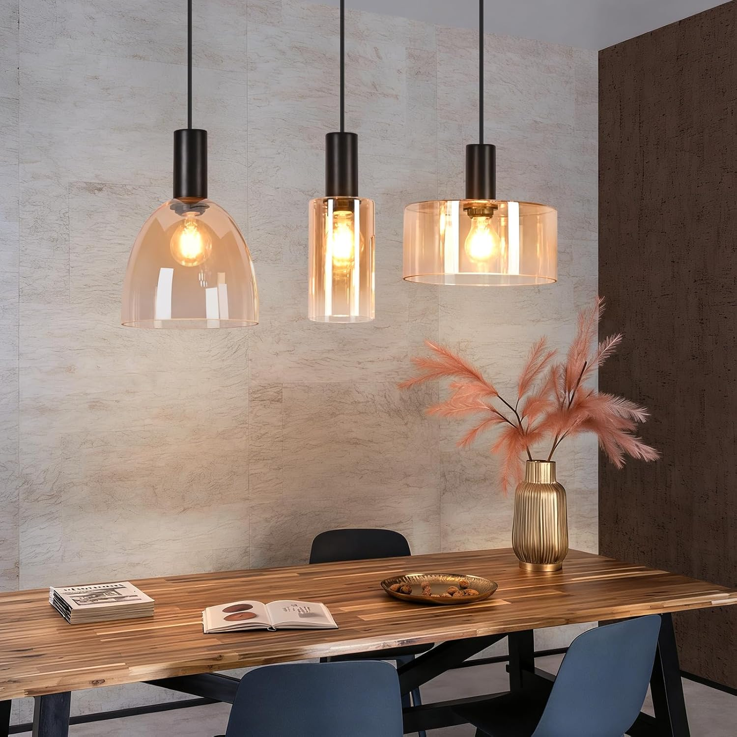 Drei moderne Hängelampen mit bernsteinfarbenem Glas hängen über einem Holztisch mit Dekoration.
