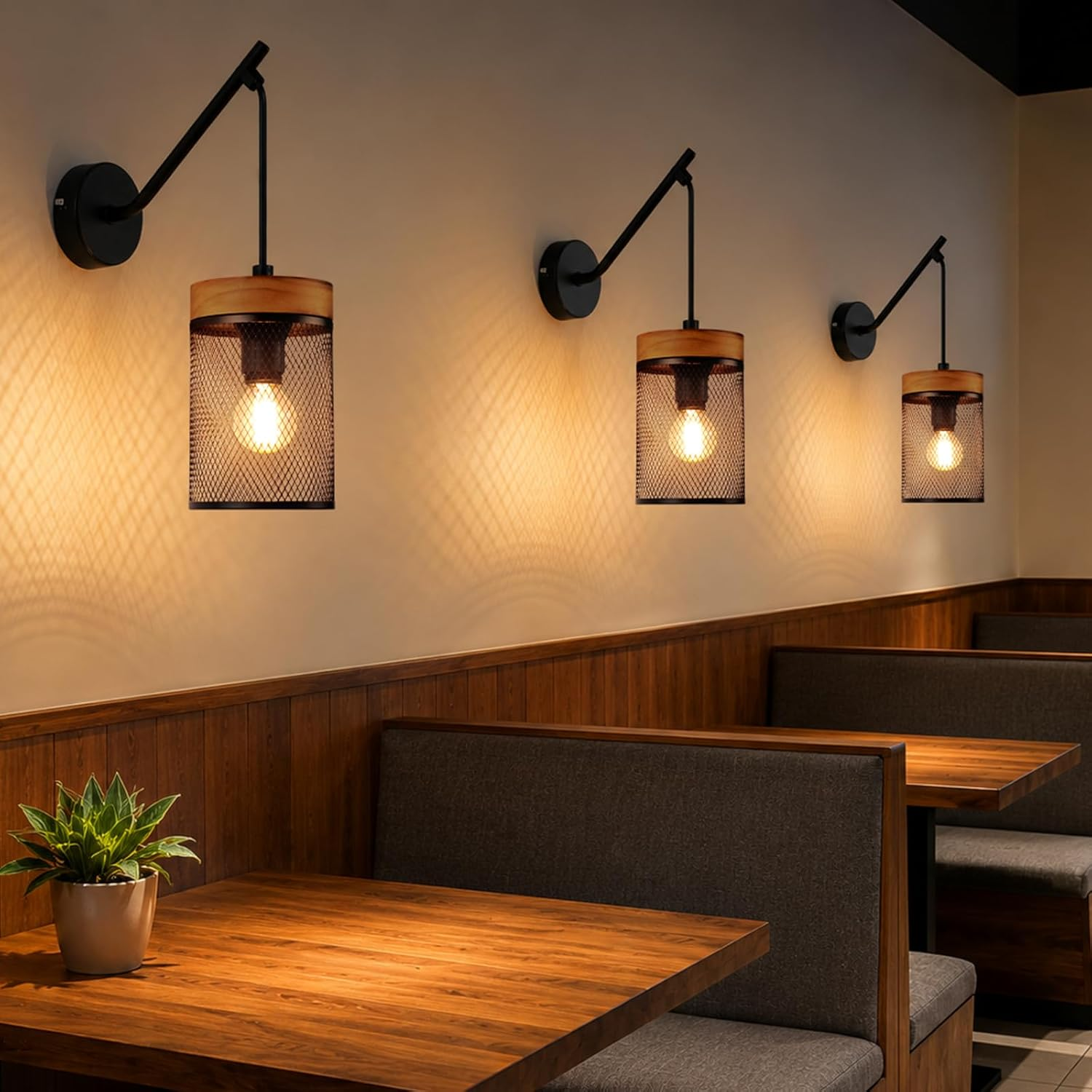 Drei Wandleuchten mit schwarzem Metall und Holz beleuchten Holztische und graue Bänke in einem Restaurant.