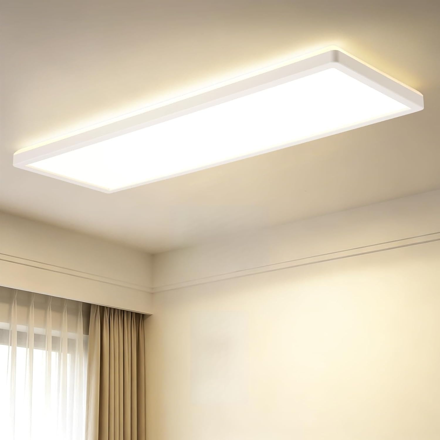 Eine rechteckige, weiße Deckenleuchte ist an einer schlichten Decke in einem Raum mit Vorhängen montiert.