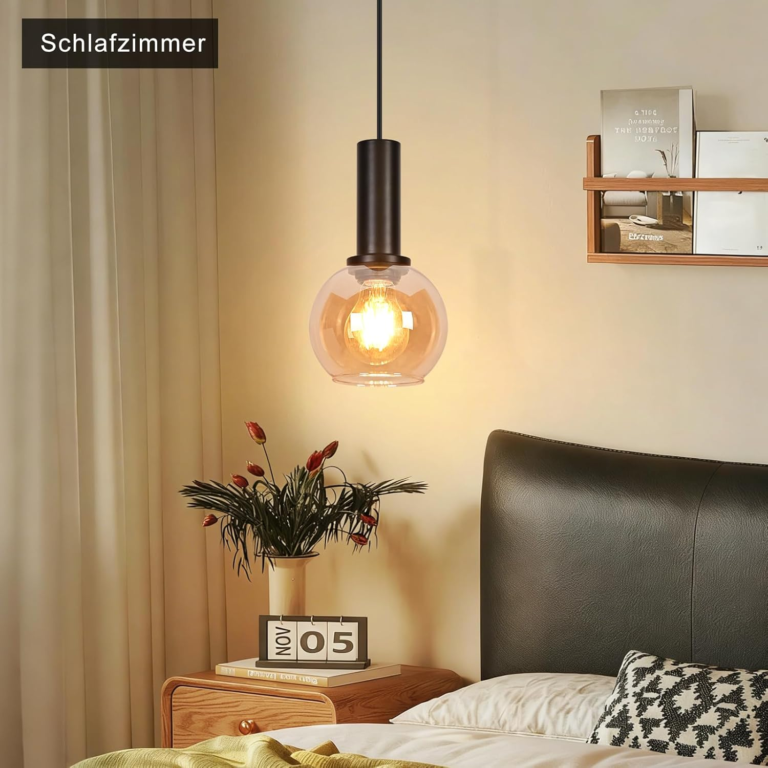 Schlafzimmer mit Hängeleuchte, Holznachtisch, Blumen und Bett mit gemustertem Kissen.