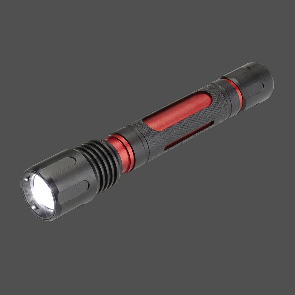 Eine schwarze und rote Taschenlampe mit eingeschaltetem Licht auf grauem Hintergrund.