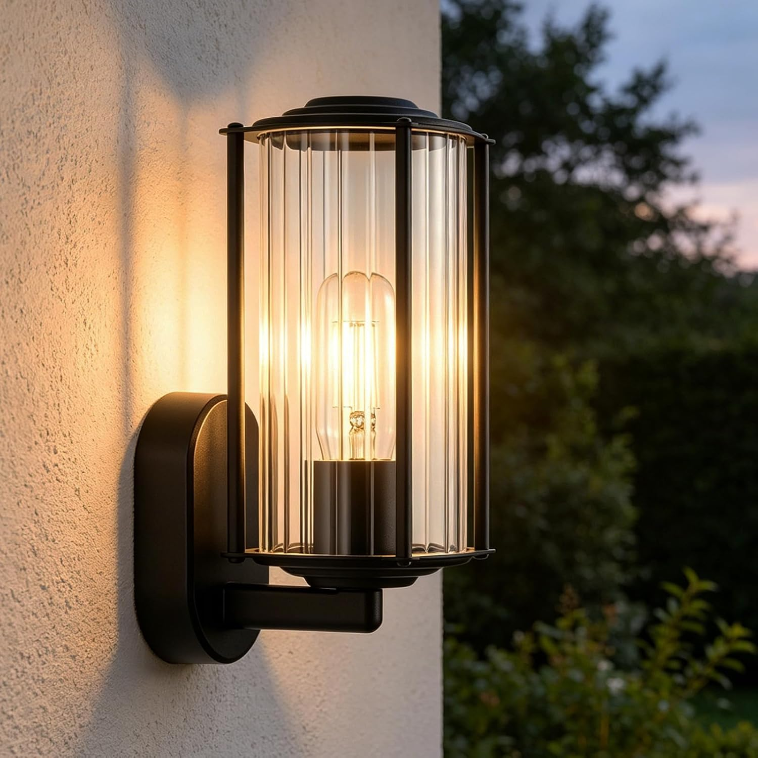 Eine schwarze Wandleuchte mit geripptem Glas leuchtet an einer Außenwand bei Dämmerung.