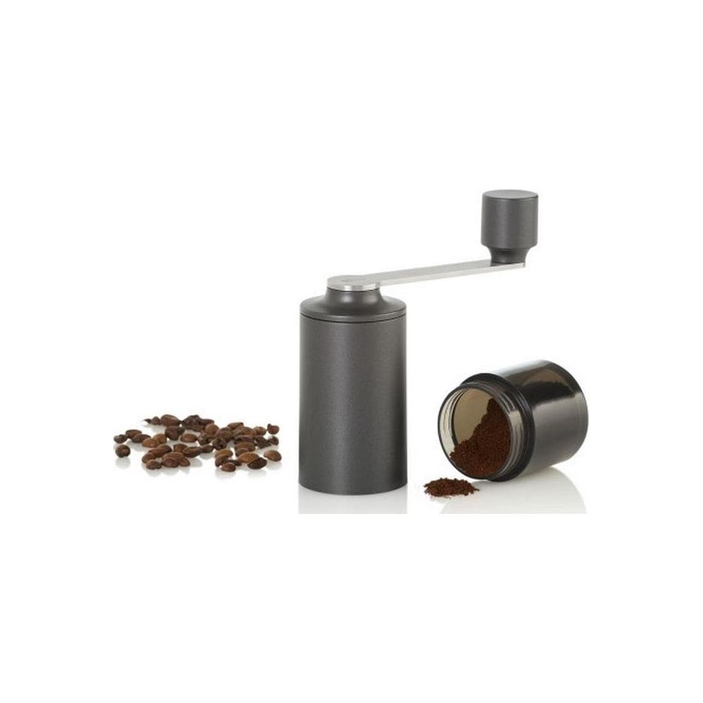 Eine graue Handkaffeemühle mit Kaffeebohnen und einer Tasse gemahlenem Kaffee.