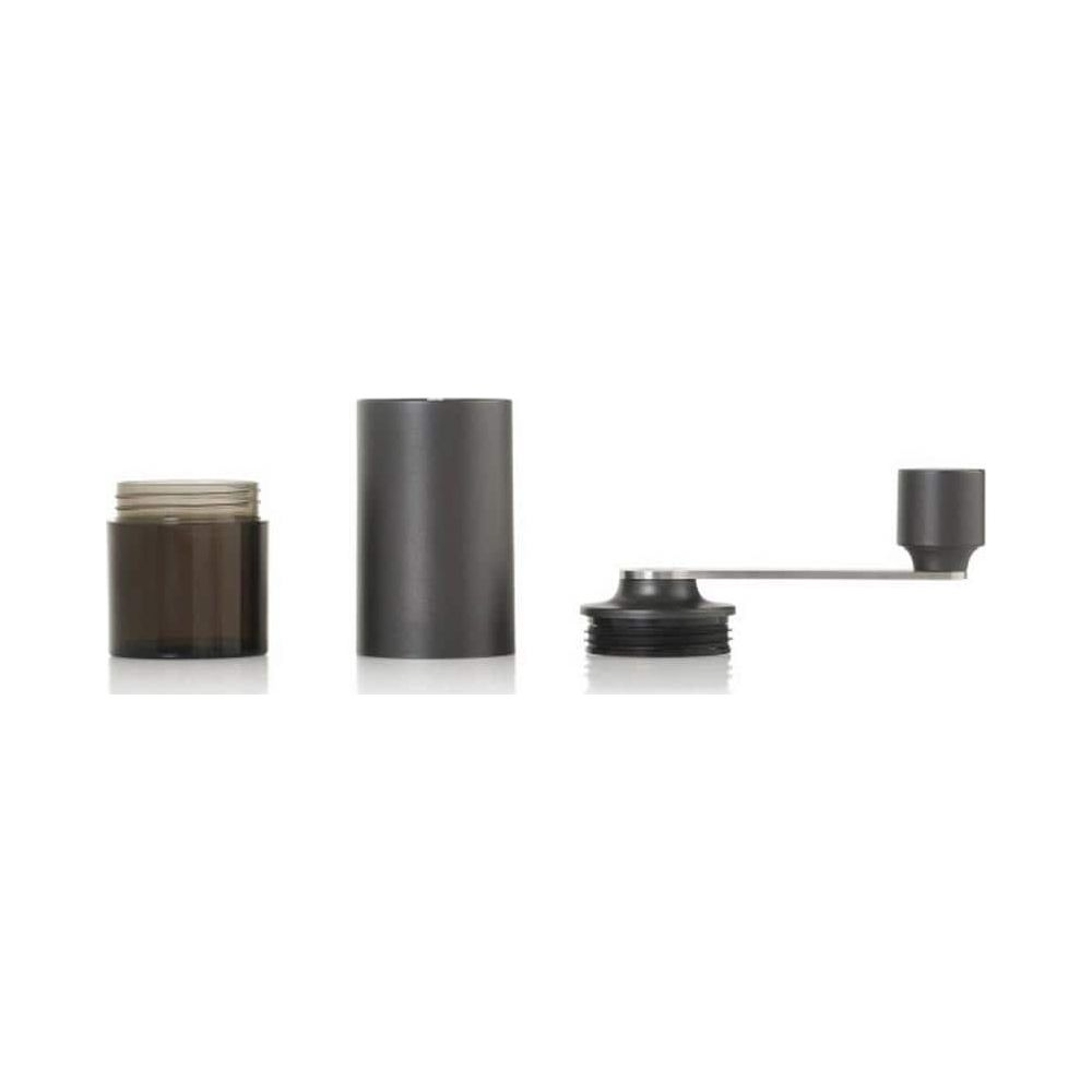 Eine zerlegte schwarze Kaffeemühle auf weißem Hintergrund mit Behälter, Hauptkörper und Kurbel.