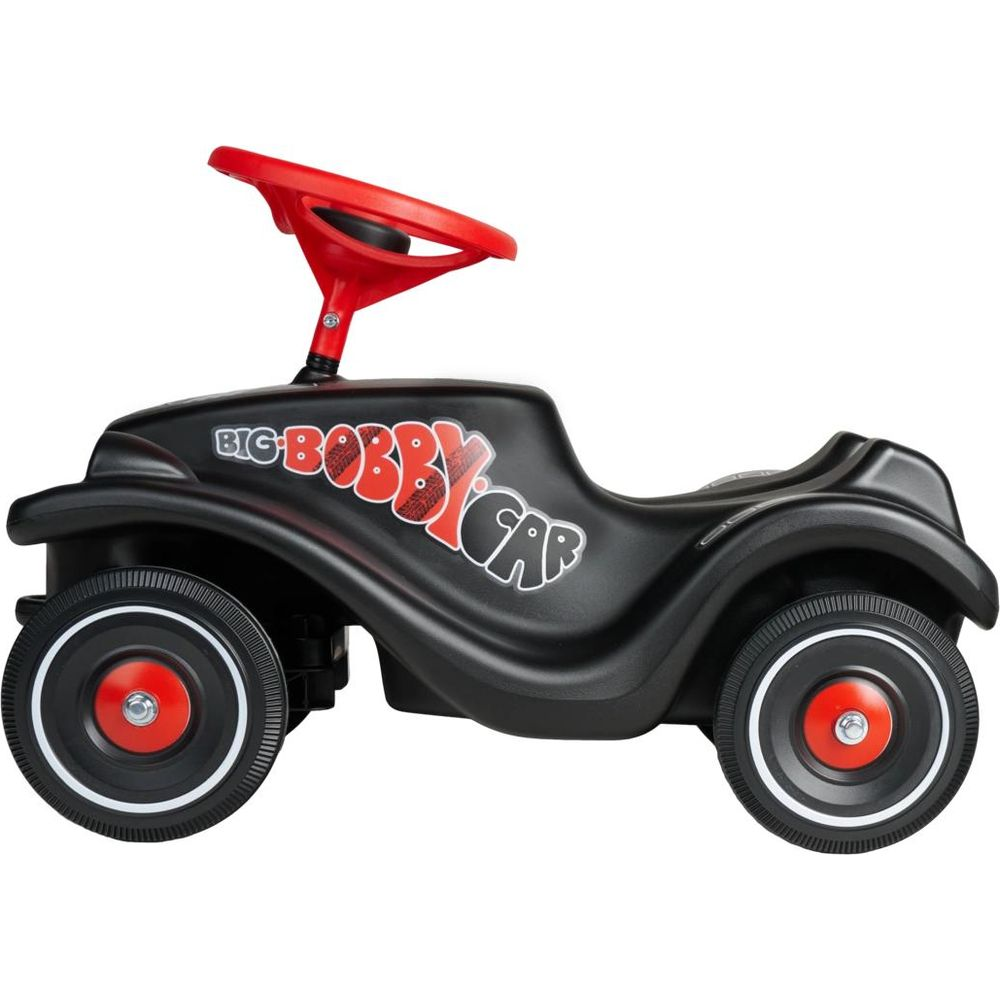 Ein schwarzes Bobby Car mit rotem Lenkrad und roten Radnaben steht auf weißem Grund.