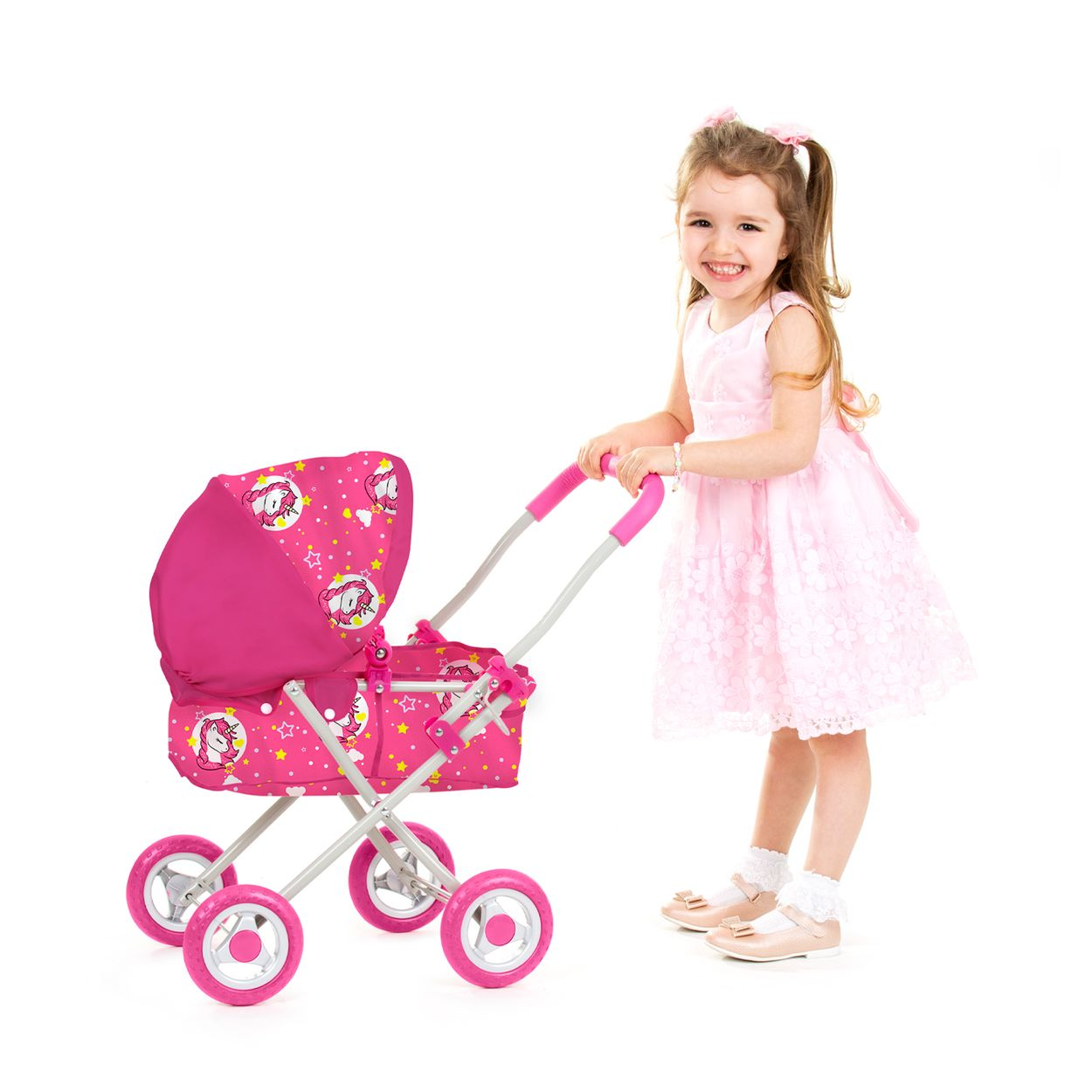 Ein lächelndes kleines Mädchen in einem pinken Kleid schiebt einen passenden pinken Puppenwagen mit Einhornmustern.