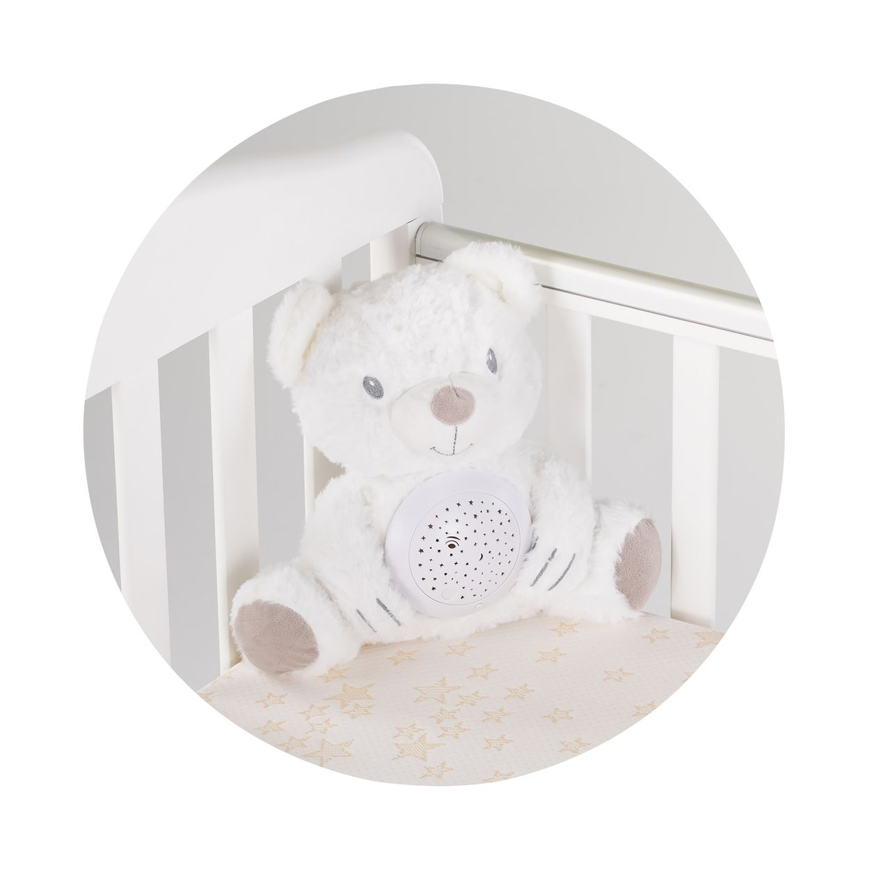 Ein weißer Plüschbär mit einem Sternenprojektor auf dem Bauch sitzt in einem weißen Babybett mit Sternenmuster.