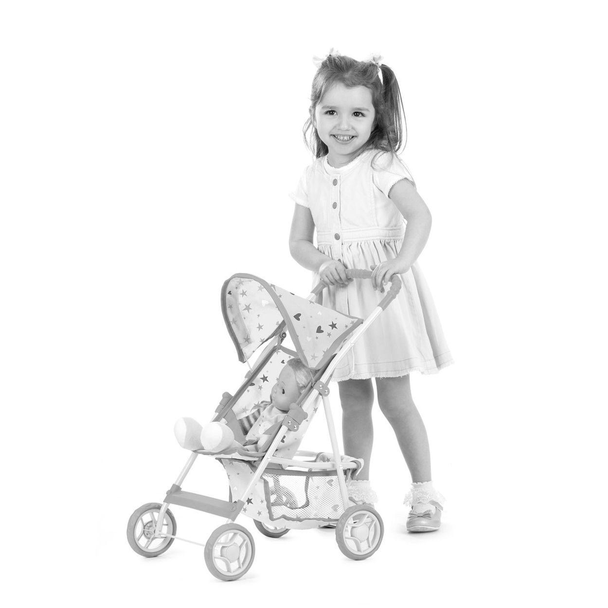 Ein kleines Mädchen in einem Kleid schiebt einen Puppenwagen mit einer Puppe darin.
